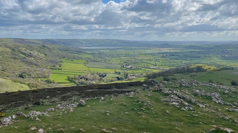 View from a craggy summit looking over fields and villages.